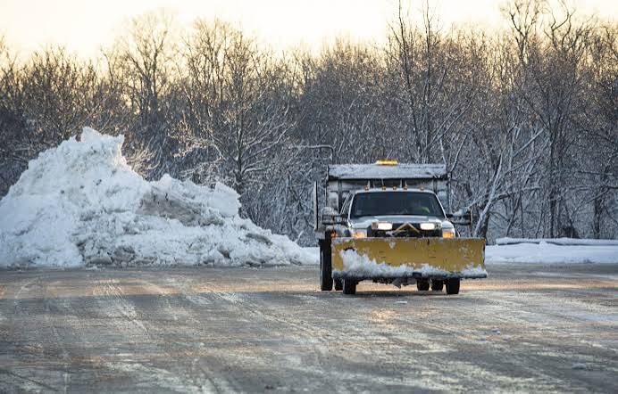 Plow truck clearing a snow-covered driveway in Grand Rapids MI by Diversified Tree Service